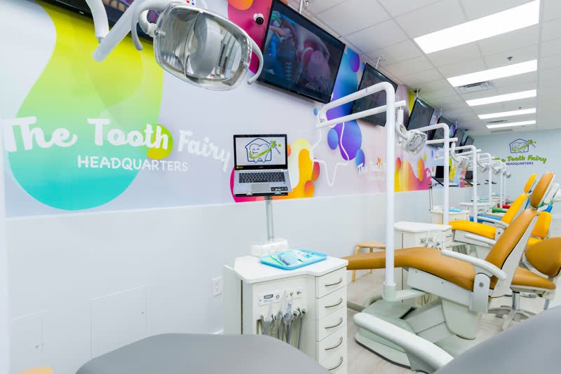 Modern pediatric dental treatment area with kid-sized chairs and ceiling TVs at The Tooth Fairy HQ